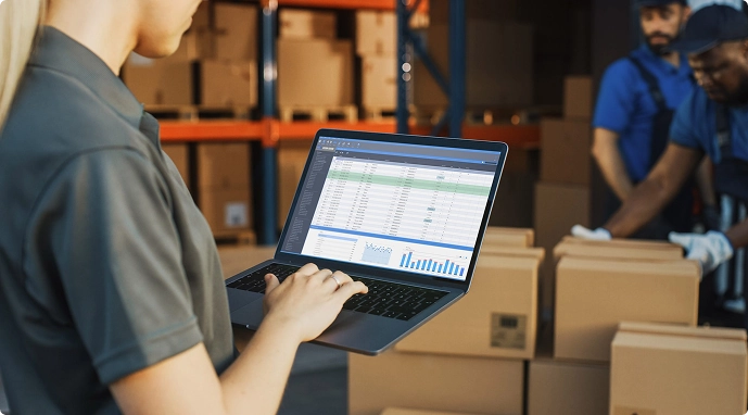 Чоловік з ноутбуком в руках стоїть у складському приміщенні